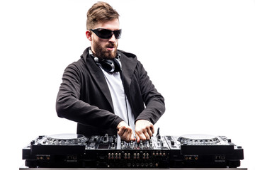 Young stylish man in black sunglasses posing with hands up behind mixing console on white studio...