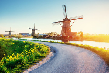The road leading to the Dutch windmills from the canal - obrazy, fototapety, plakaty