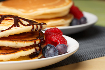 Pile of Pancakes with blueberries and raspberries and chocolate sauce
