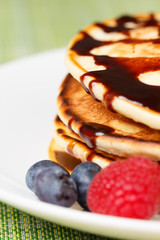 Pile of Pancakes with blueberries and raspberries and chocolate sauce
