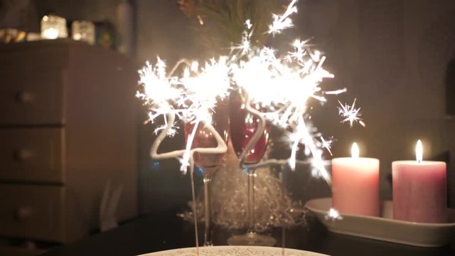 Christmas tree shaped sparkles with two glasses of champagne and candles