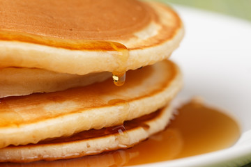 Pile of Pancakes with blueberries and raspberries and maple syrup dripping