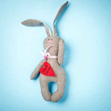 Easter bunny on a blue background. Rabbit. Easter ideas. Easter eggs. Space for text. Black lettering on a heart happy easter.