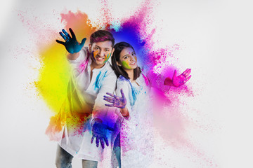 Indian Couple showing their colored hands or with pichkari or sweet laddu on Holi festival,...