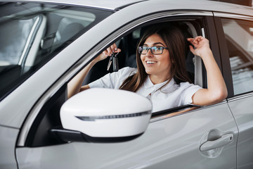 Young happy woman near the car with keys in hand