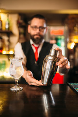 Barman with shaker behind a bar counter