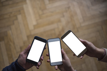 Three hands holding smart phones