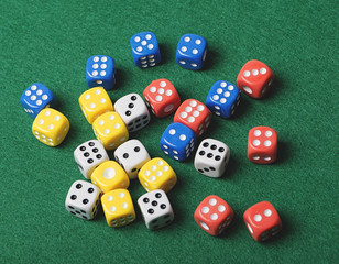 Dice of various colors on green background. Horizontal shoot.
