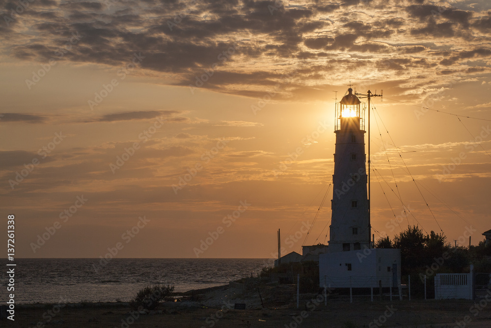 Wall mural view at the sea with sun lighting through lamp of lighthouse