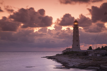 Fototapeta na wymiar pink sunset with clouds behind the old lighthouse