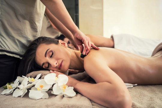 Woman enjoying traditional hot stone massage next to her partner