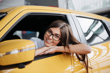 Young woman in her new car smiling
