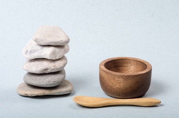 A stacked Zen stones with a wooden little spoon and a wooden little bowl. - obrazy, fototapety, plakaty