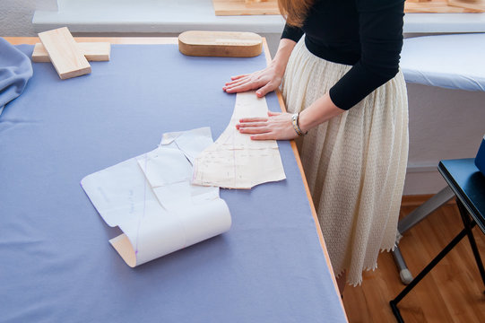 Seamstress hands on the work table with pattern. Style and design development and creating garment, clothes sew and repair service, seamstress at work concept (soft focus)