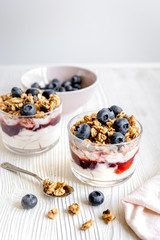 Cooking breakfast with granola and berries on white kitchen background