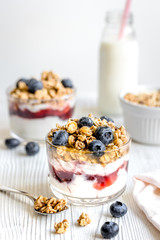 Homemade fitness granola with yoghurt and berries on white kitchen background
