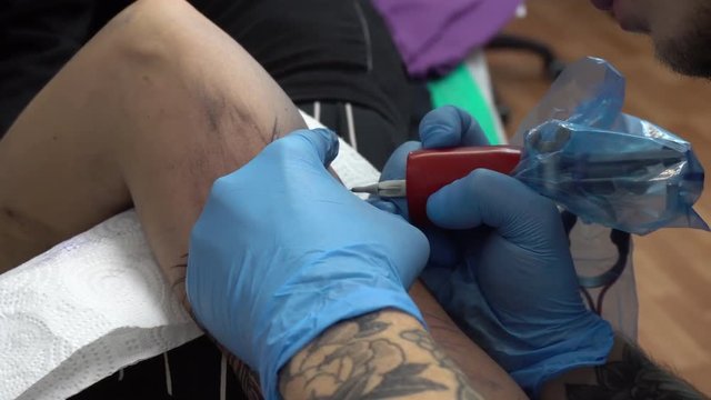Tattoo artist make tattoo on the arm. Process of tattooing. Close up