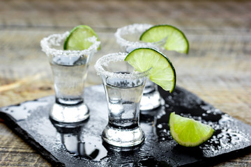 Party in bar with tequila, salt and lime on wooden table