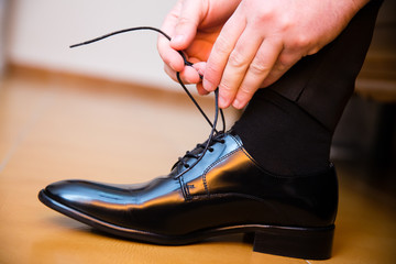 Groom putting his wedding shoes