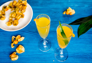 cocktail with physalis in glass on wooden background