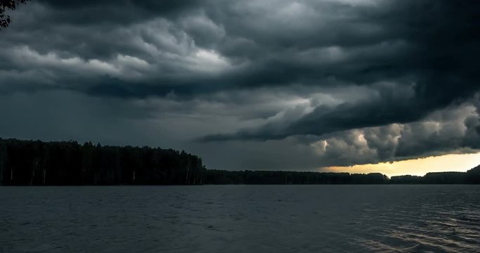 Dark stormy clouds float across the sky. Storm mooving over the river. Time lapse of storm clouds moving fast