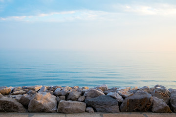 Fototapeta na wymiar peaceful quiet rock pier at sunrise with calm blue sea waves