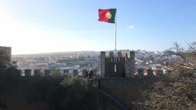 People On Top of Sao Jorge Castle With Portugal Flag. Sao Jorge is a Moorish castle occupying a commanding hilltop overlooking the historic centre of the city of Lisbon and Tagus River.