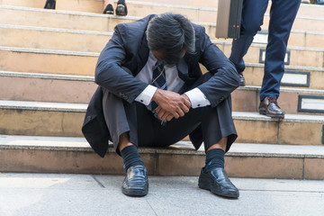 Businessman sitting on the stairs fixing a failing sense.