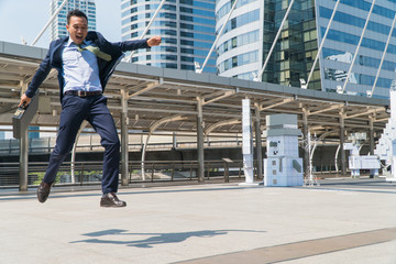 Young businessman jumping with joy in success. Focus is on the left