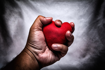 angry man crushing red heart in hand., unrequited love., love concept for valentines day., in dark tone.