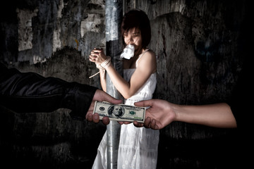 Human trafficking concept., Person hand with a dollar banknote buying victim woman in pain and bound hands with rope., missing kidnapped., in dark tone.