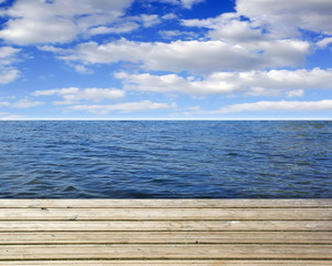 Fototapeta premium Wooden plank with sea or ocean and blue sky, copy space for individual text