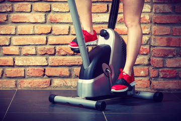 Active woman using exercise bike at the gym.