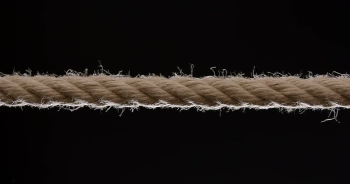 Close shot of rope being pulled across the frame against black