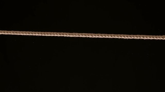 Length of rope being pulled tight across frame against black