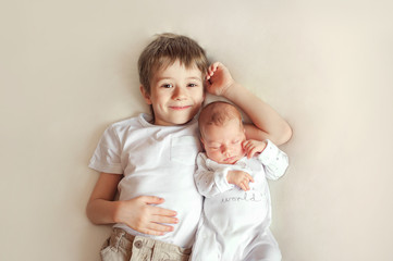 Little brother hugging her newborn baby. Toddler kid meeting new sibling. Cute boy and new born...