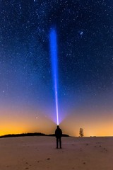 Starry sky and man with flashlight. Winter night landscape.