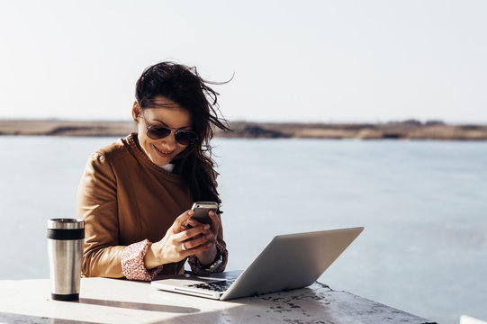 Charming woman working outside, typing a message on mobile