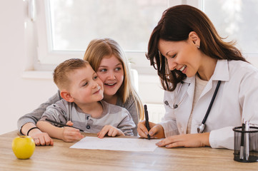 Beautiful female doctor playing with kids at doctor's. Doctor isn't scary. © bnenin