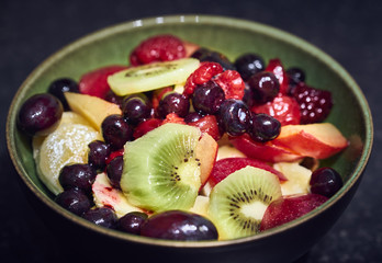 A green bowl with a mix of healthy fruit salad 