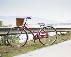 Fototapeta premium Vintage red bicycle beside river road