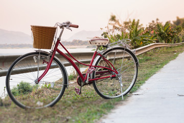 Vintage red bicycle beside river road