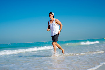 Sporty teenager in sportswear jogging at beach looking happy.