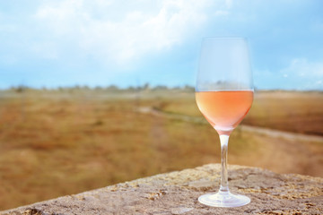 Glass of red wine on stone on blurred natural background