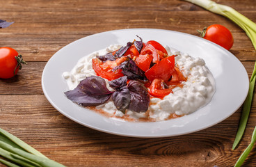 Salad with cottage cheese and tomatoes on wood table.