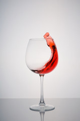 glass red wine splashing on a white background
