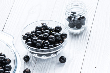 black currant in glassware on white wooden table