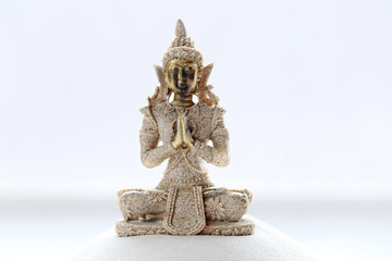 Smiling Buddha statue beige on white fine sand 
