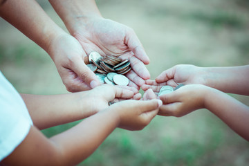 Mother and children holding coin in hands as saving money concept in vintage color tone