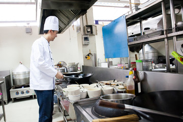 Chef in hotel or restaurant kitchen busy cooking